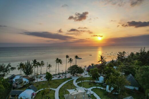 A breathtaking aerial view of Kizimkazi Beach at sunset, showcasing vibrant skies and serene waters in Tanzania.