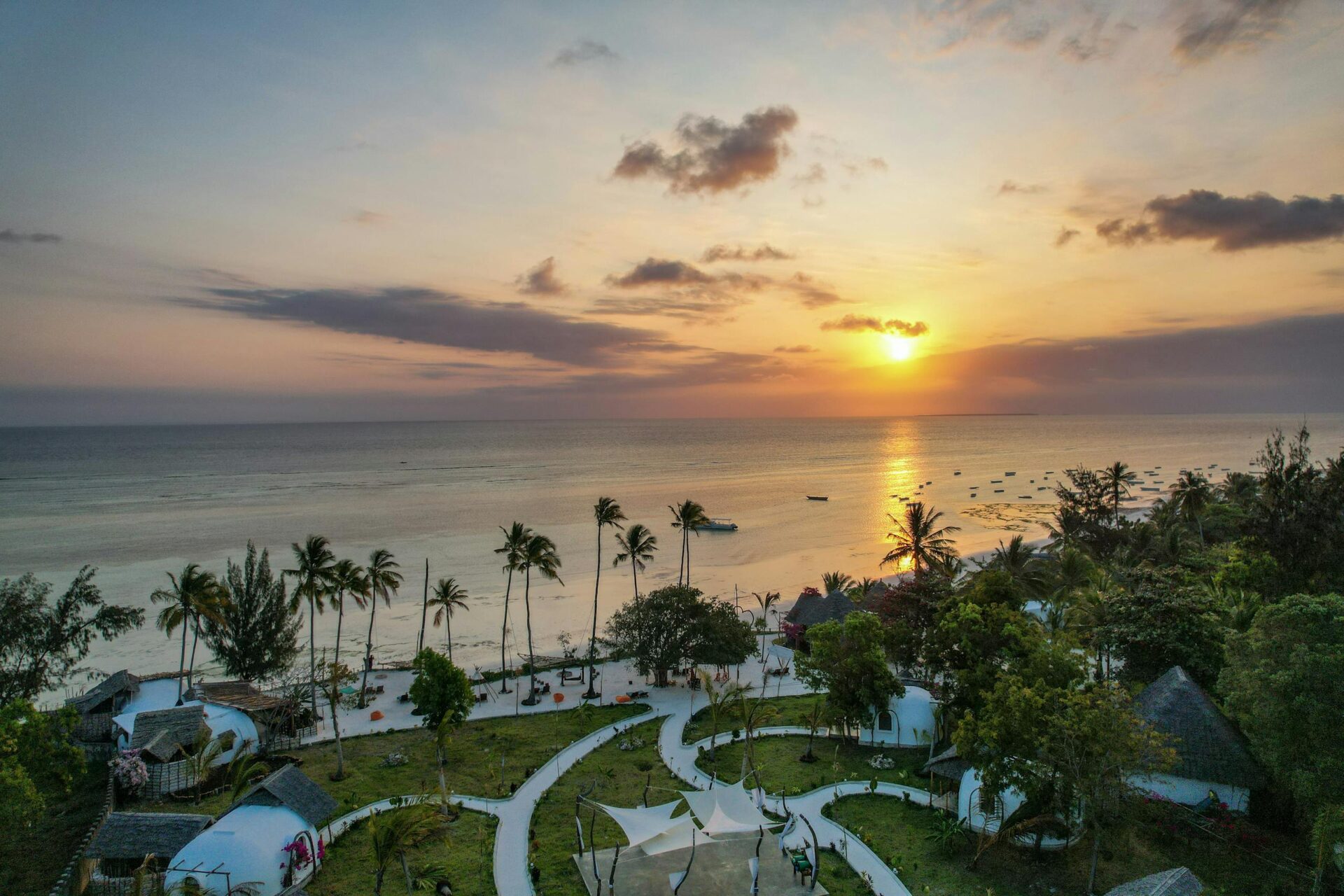 A breathtaking aerial view of Kizimkazi Beach at sunset, showcasing vibrant skies and serene waters in Tanzania.