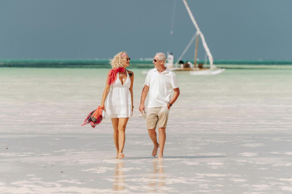 Elderly couple enjoys a peaceful walk on a pristine Zanzibar beach.